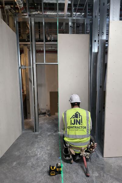 JN Contractor LLC worker using laser level on commercial project